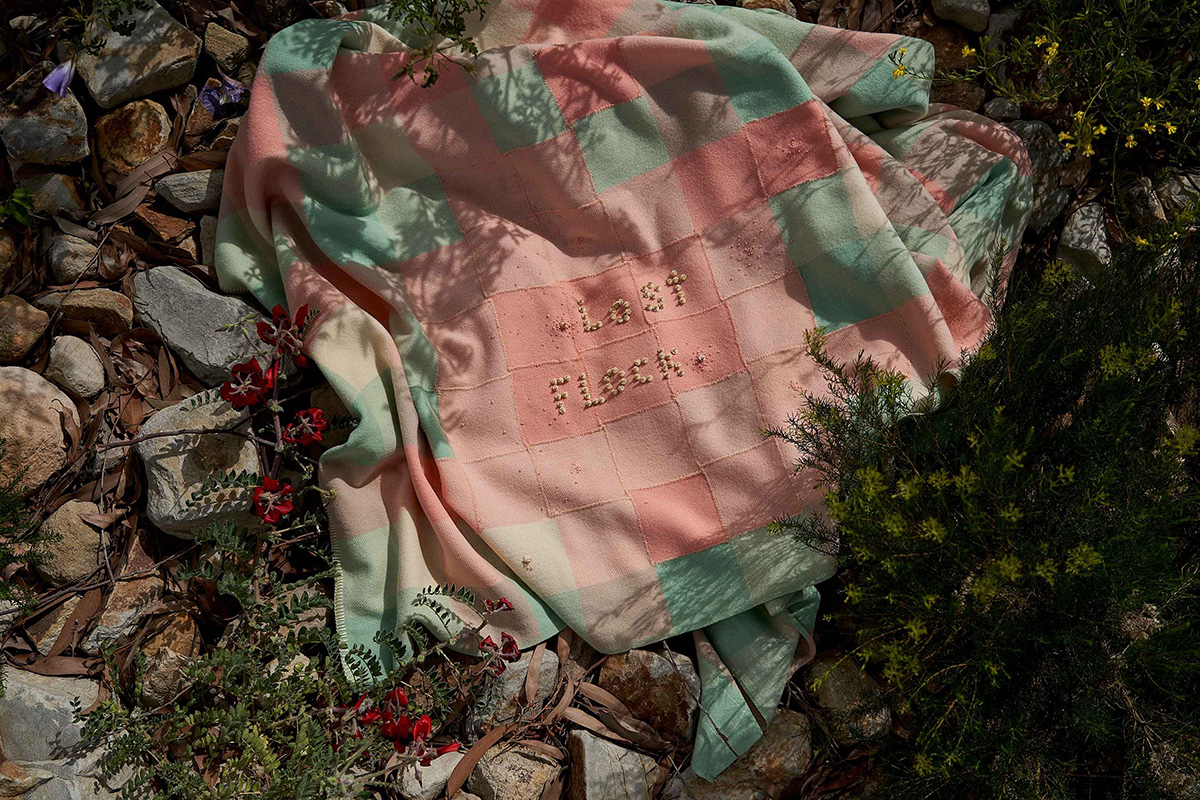 Image shows a blanket with "lost flock" stitched onto it.