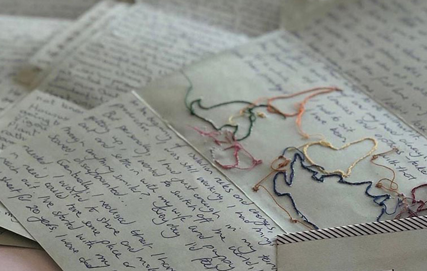 Close up of handwritten letters. One has colourful stitiching.