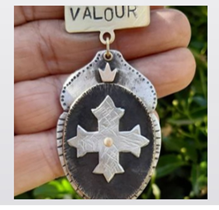 Image shows a hand holding a metal medal with "valour" stamped on it.
